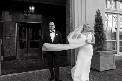 Bride’s veil flows dramatically as couple exits elegant venue