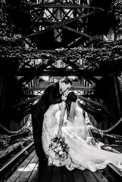 black and white photo of bride and groom dipping under bridge in downtown cleveland capture by cleveland wedding photographers