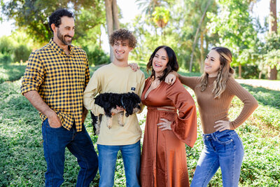 family smiles and holds dog