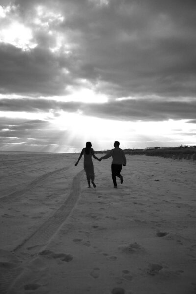 Silhouette of couple running through the dunes of West Hamptons.