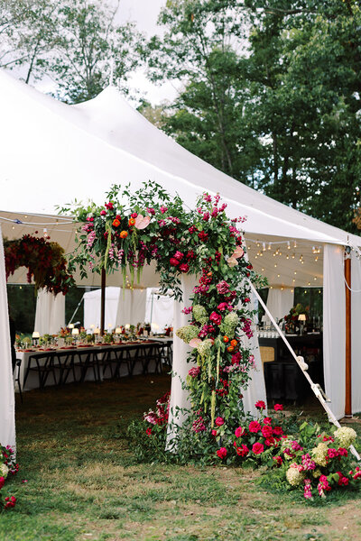 bright pink and orange flowers on the entrance to a tent for a wedding reception