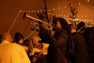 Band playing the horns at fall tent wedding with ambient lighting