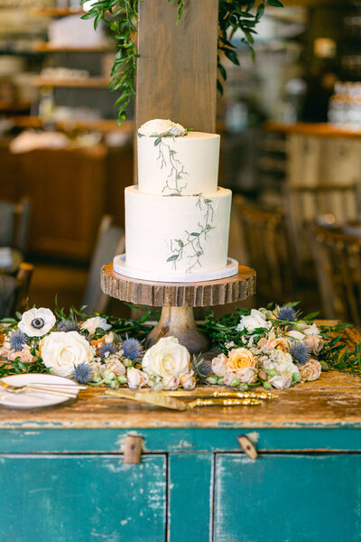 This elegant photograph captures a beautifully designed wedding cake at River Café in downtown Calgary, showcasing the charming details of a memorable reception.