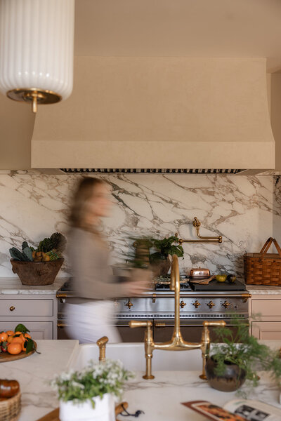 Tracy Greenstein walking through her kitchen in soft motion blur, reflecting a vibrant, lived-in wellness lifestyle