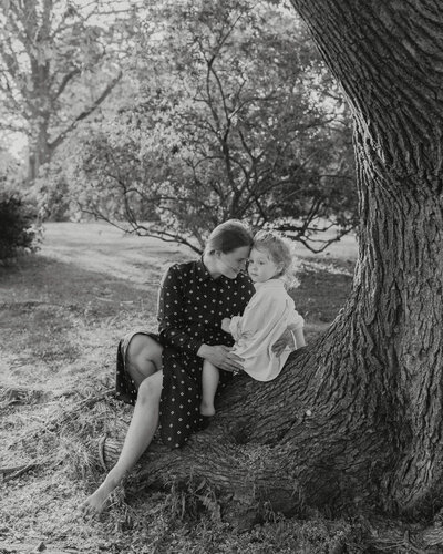 Mother and her son sitting by a tree heads together on a summer evening in Tähtitorninvuori in Helsinki