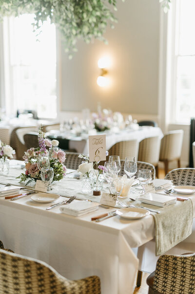 Beautifully set guest tables with florals, and white linens at the Inn on Officer's Garden dinging room in Calgary