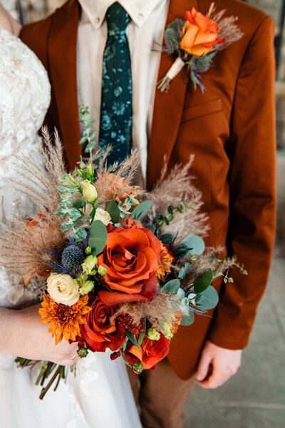 Detail photo of bride holding a fall bouquet with orange flowers