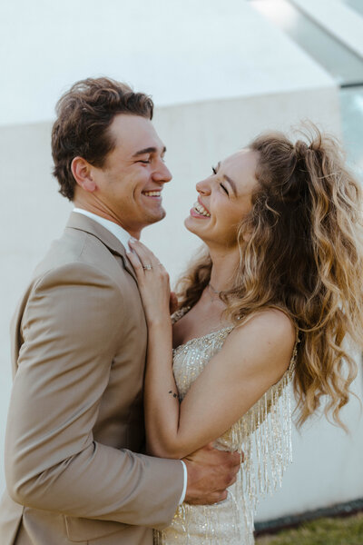 bride and groom laughing while holding each other