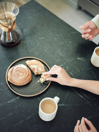 a couple shares Fika, cinnamon rolls, coffee at Fernhaus, Northern Michigan during a designer brand photoshoot on film