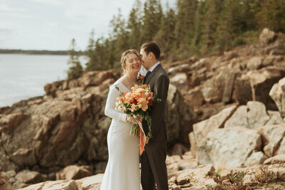 bride and groom laughing on a cliff in Acadia National Park after just getting eloped in Maine