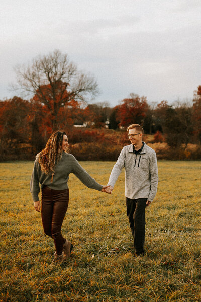 couple laughing holding hands in sand dunes