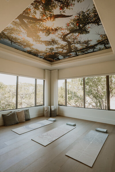 Room with yoga mats and painting of trees on the ceiling