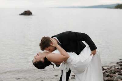 A person dipping their partner by the ocean on their wedding day 