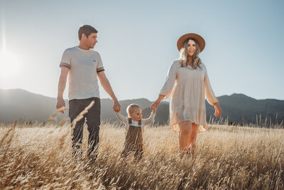 a family photoshoot in wanaka, parents and one child walking through the long grass