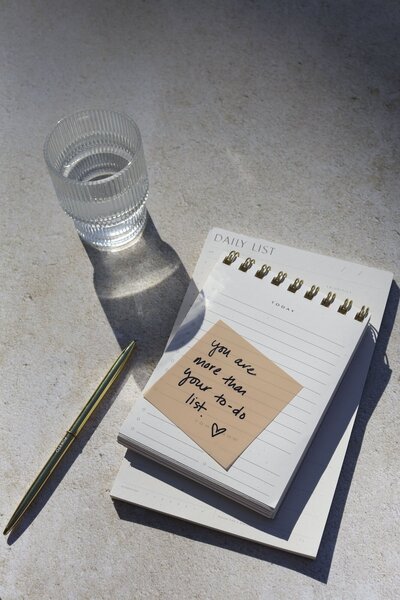 Notepad next to a glass of water with words "You are more than your to-do list"