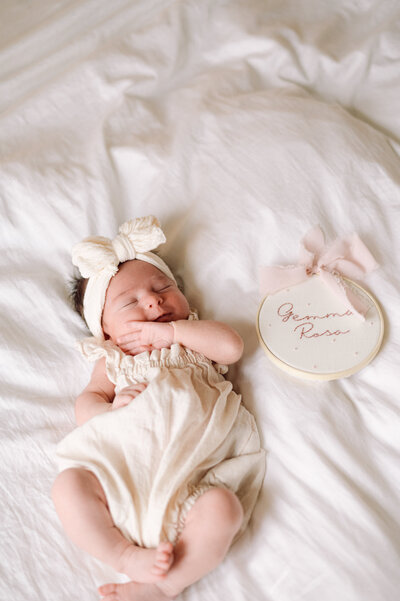 Newborn baby resting beside a name sign during an in-home session, captured by a Northern Virginia family photographer in natural light.