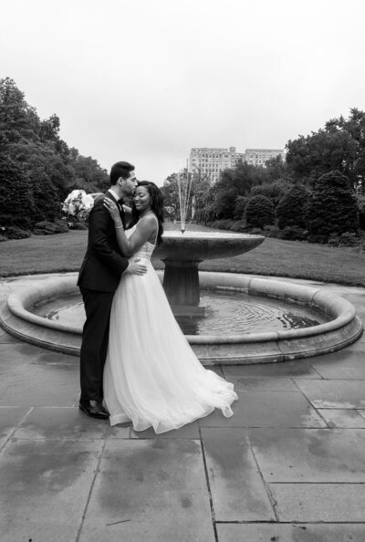 bridal couple kissing in front of the beautiful fountain in Brooklyn Botanical Garden.