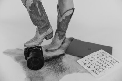 Black and white cowboy boots resting on a Canon camera