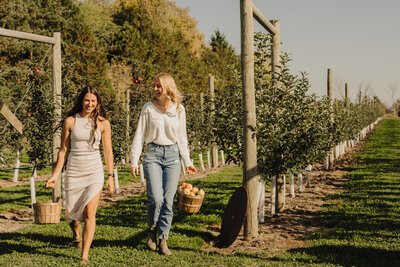 Bride and friend strolling through orchard rows at Applebottom Orchards.