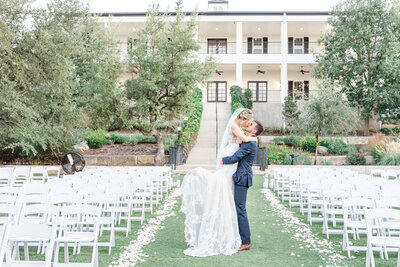 A bridge and groom kiss on a tree swing in front of the Kendall Point lake.