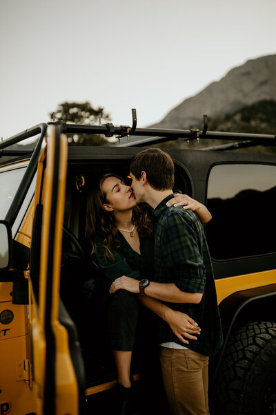 man holding fiancé in a yellow jeep about to kiss