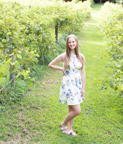 Teenage girl smiles in floral dress in a vineyard