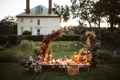 Romantic outdoor styled wedding picnic with candles, florals, and charcuterie in front of a historic Maine estate.