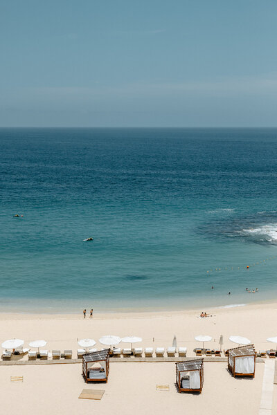 Luxury beachfront at Hilton Resort in Cabo, with white sand, turquoise ocean, cabanas, and umbrellas.