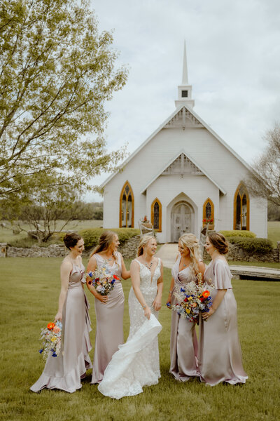 bride and bridesmaids in front of open air chapel taken by dallas wedding photographer