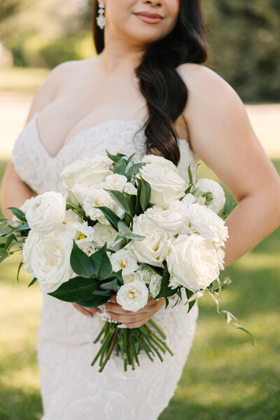 bride holding bouquet with curled hair draped over her shoulder