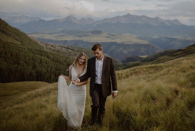 Bride and groom walk through the Telluride Mountains