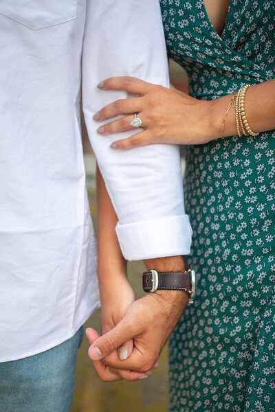 Close up of engaged couple holding hands showing off ring