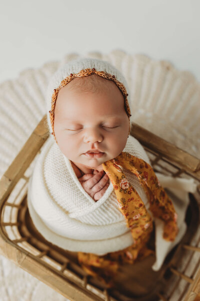 newborn boy swaddled in navy blue sleeping in a moon shaped wooden prop for his york newborn photo session