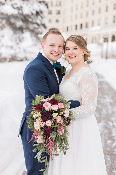 Bride and groom holding each other in front of wedding venue in Lake Louise, AB.
