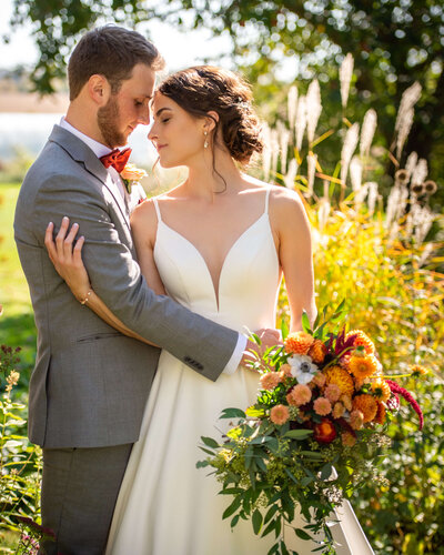A fall ottawa wedding at Strathmere showing a bride holding a fall bouquet and hugging her groom