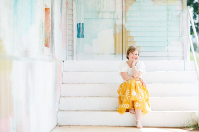 Woman in a yellow skirt sitting on stairs outside