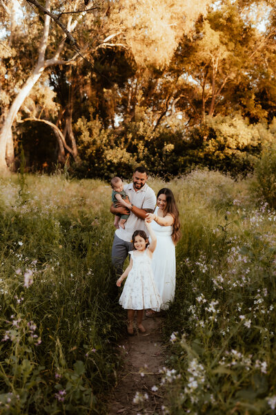 A family of four walking through a stunning wildflower field at golden hour. 