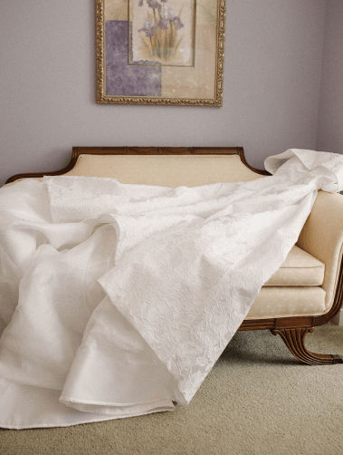 A picture of a wedding dress laid across a couch before the bride puts it on