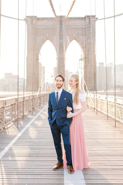 married couple posing on Brooklyn Bridge at sunrise