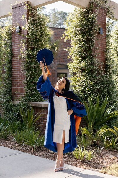 uf grad posing with cap and gown on university of florida campus