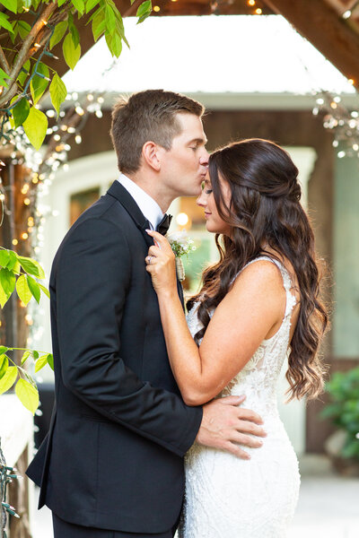 bride and groom embracing while holding a colorful flower bouquet