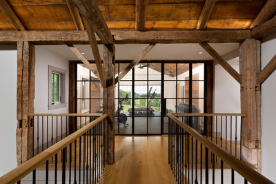 Wooded hallway looking at a glass window pane wall into a gym 