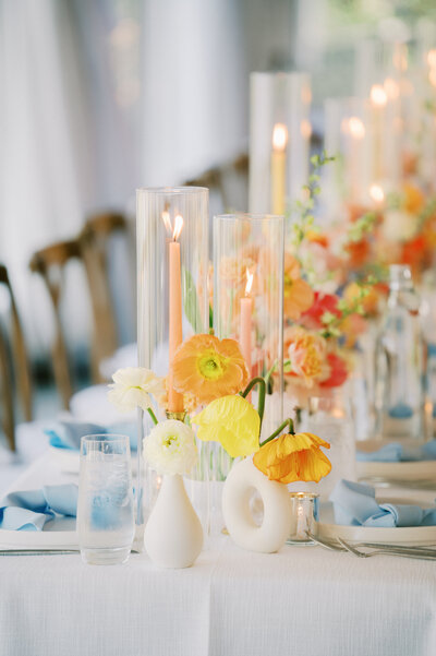 unique yellow and orange floral arrangement with blue tablescape at humming bird house wedding venue in austin tx, by austin wedding photographer