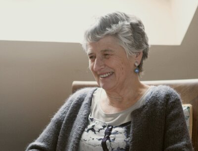 Photo d'Anne Mathieu assise sur une chaise en train de rigoler