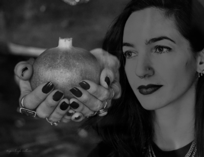 Founder of Alchemy Queen holding pomegranate in hands representing the archetype of Persephone, a leading guide in the Animal Communication Course. 