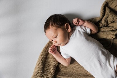 Newborn baby resting on a blanket with eyes closed during an at-home newborn photography session.