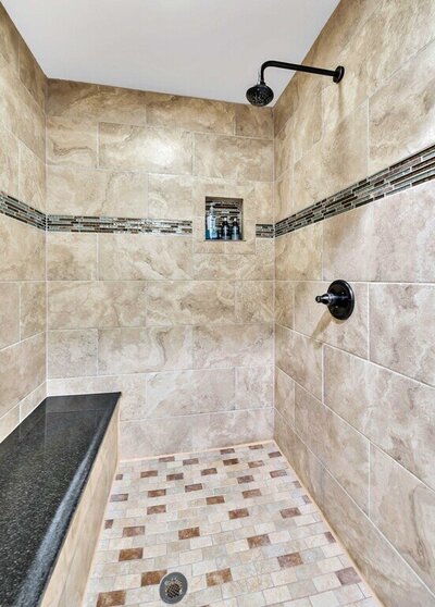 Large shower with granite tile and bench seating in this 4-bedroom- 4-bathroom historical home with guest house on 3 acres of land in the greater Waco area.