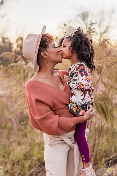 mother and daughter kiss in a field during motherhood session in Livingston.