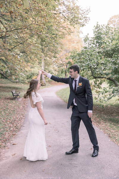 Bride and groom twirling at the park