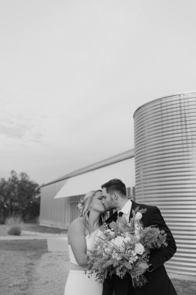 couple kissing in front of barn silo